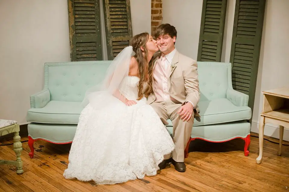 blue vintage rentals couch with bride and groom kissing that started this wedding venue rental business