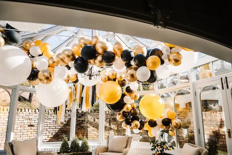 White, Black, and Gold Balloon Garland hanging from the ceiling